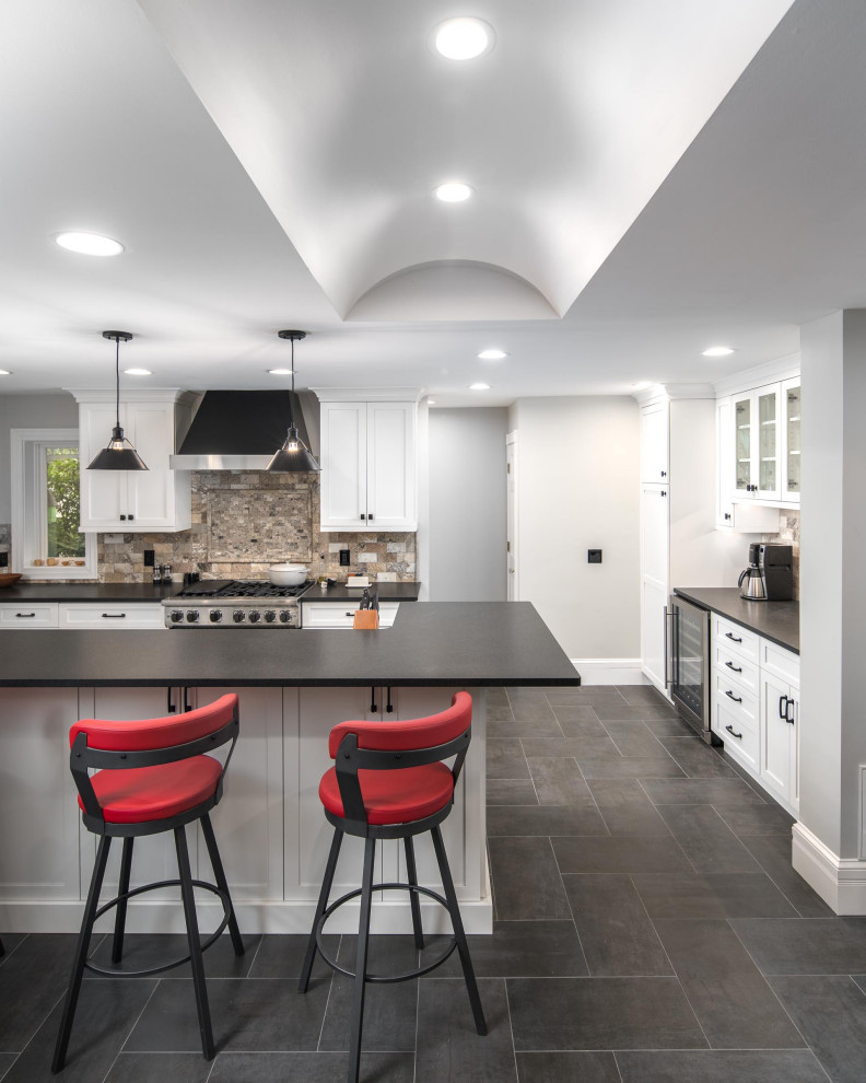 Immagine di un cucina con isola centrale moderno con ante in stile shaker, elettrodomestici in acciaio inossidabile, pavimento grigio e top nero