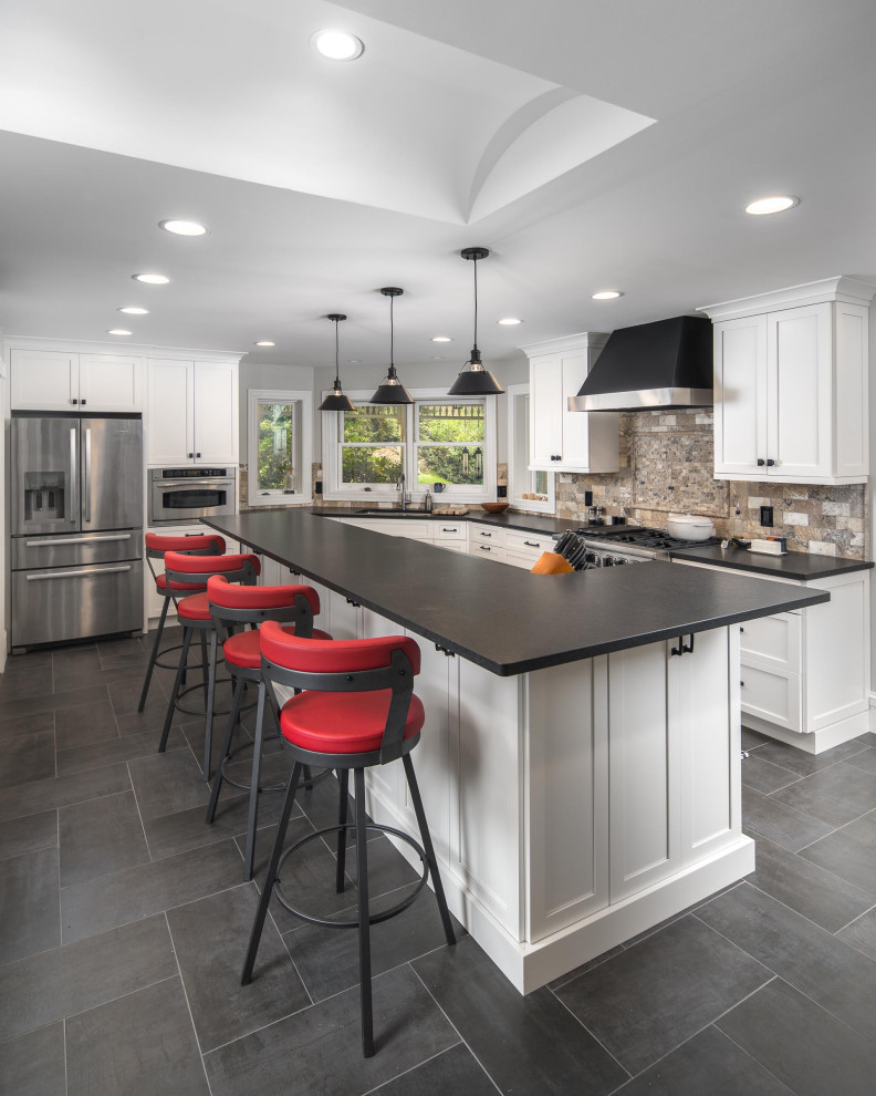 Design ideas for a classic kitchen in Charlotte with shaker cabinets, stainless steel appliances, an island, grey floors and black worktops.