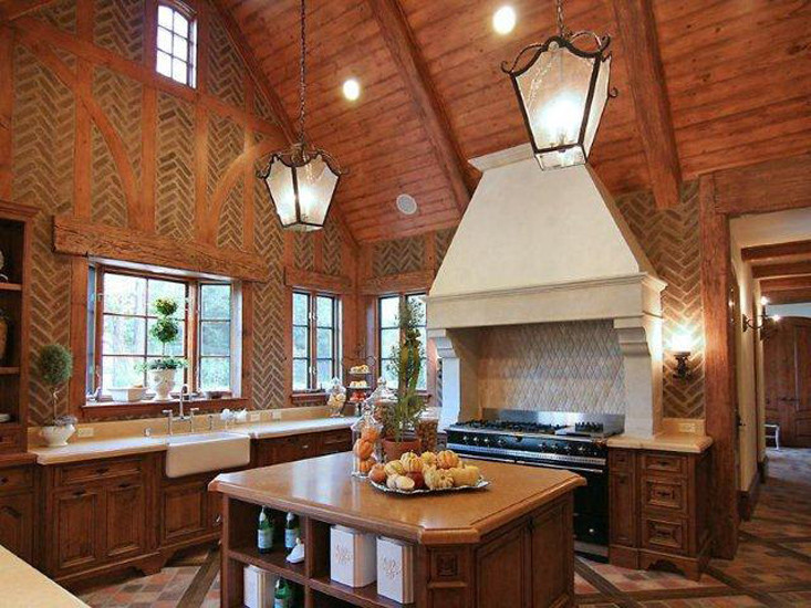 Immagine di una cucina chic di medie dimensioni con lavello stile country, ante con riquadro incassato, ante in legno bruno, paraspruzzi in mattoni, elettrodomestici in acciaio inossidabile e pavimento in mattoni