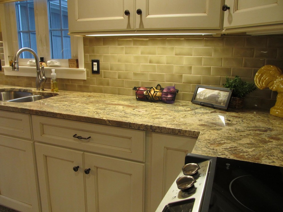 This is an example of a medium sized l-shaped kitchen/diner in New York with a submerged sink, recessed-panel cabinets, beige cabinets, granite worktops, green splashback, metro tiled splashback, stainless steel appliances, no island and multicoloured worktops.