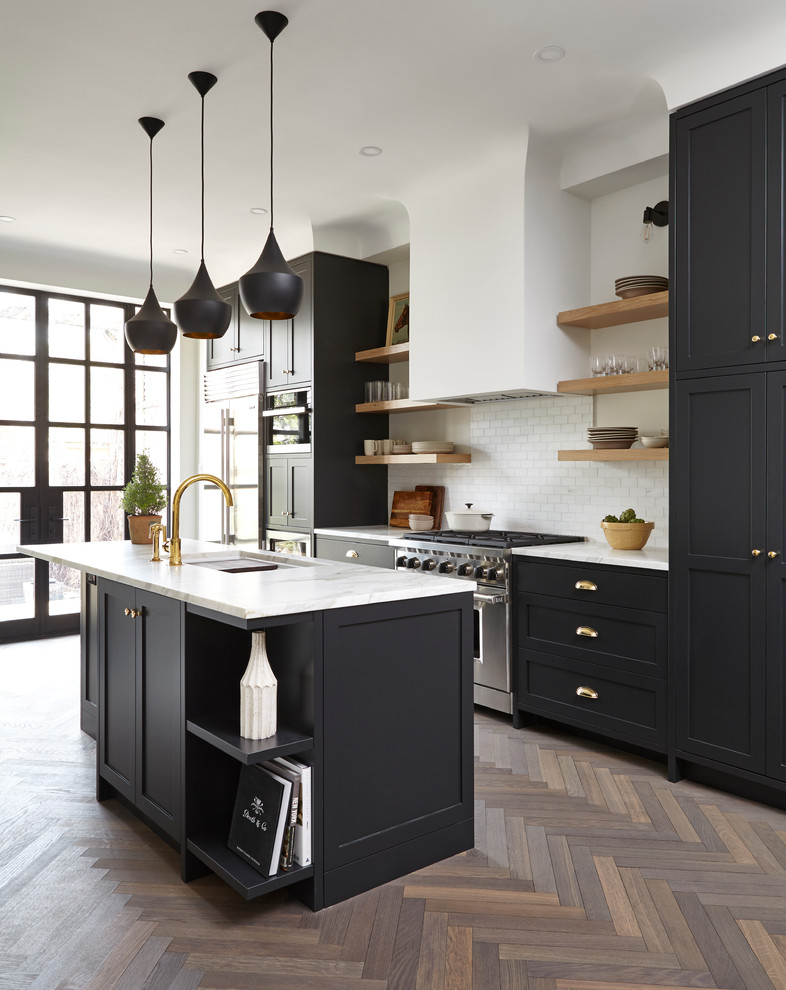 Example of a mid-sized transitional single-wall medium tone wood floor and brown floor enclosed kitchen design in Toronto with an undermount sink, shaker cabinets, white backsplash, subway tile backsplash, stainless steel appliances, an island, marble countertops and white countertops