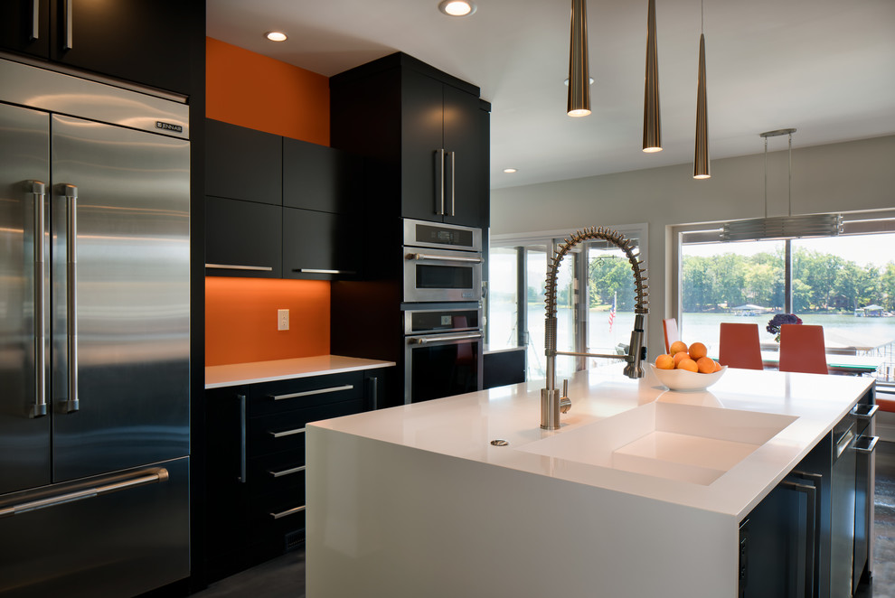 Idéer för att renovera ett stort funkis kök, med en integrerad diskho, släta luckor, svarta skåp, bänkskiva i kvarts, orange stänkskydd, rostfria vitvaror, betonggolv, en köksö och grått golv