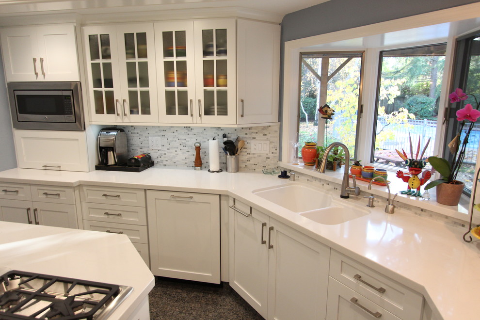 Klassisk inredning av ett mellanstort kök, med en undermonterad diskho, skåp i shakerstil, vita skåp, bänkskiva i kvarts, grått stänkskydd, stänkskydd i glaskakel, rostfria vitvaror, marmorgolv och en köksö