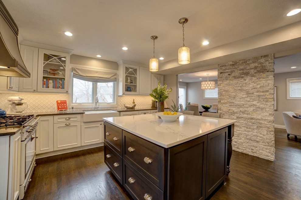 Example of a medium tone wood floor eat-in kitchen design in Other with glass-front cabinets, dark wood cabinets, quartz countertops, white backsplash, an island, white countertops and a farmhouse sink