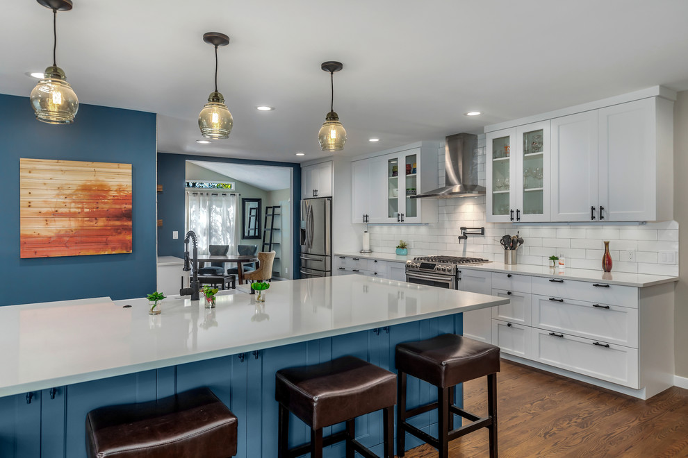 Eat-in kitchen - large transitional l-shaped dark wood floor and brown floor eat-in kitchen idea in Portland with a farmhouse sink, recessed-panel cabinets, quartz countertops, white backsplash, subway tile backsplash, stainless steel appliances, an island and white countertops