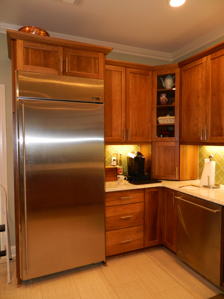 Exempel på ett avskilt, litet modernt l-kök, med en undermonterad diskho, skåp i shakerstil, skåp i mellenmörkt trä, granitbänkskiva, grönt stänkskydd, stänkskydd i glaskakel, rostfria vitvaror, klinkergolv i porslin och en halv köksö