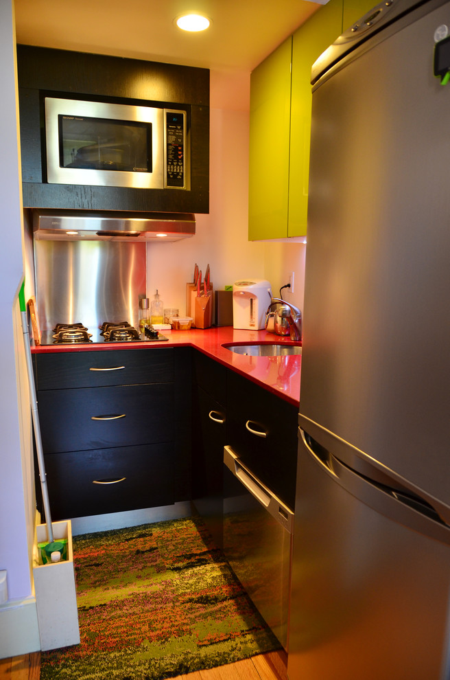 Imagen de cocinas en L moderna pequeña sin isla con fregadero encastrado, armarios con paneles lisos, puertas de armario verdes, encimera de cuarcita y suelo de madera en tonos medios
