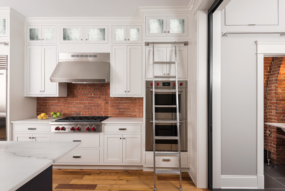 Design ideas for a medium sized classic l-shaped kitchen/diner in Boston with a submerged sink, shaker cabinets, white cabinets, marble worktops, red splashback, stainless steel appliances, medium hardwood flooring and an island.