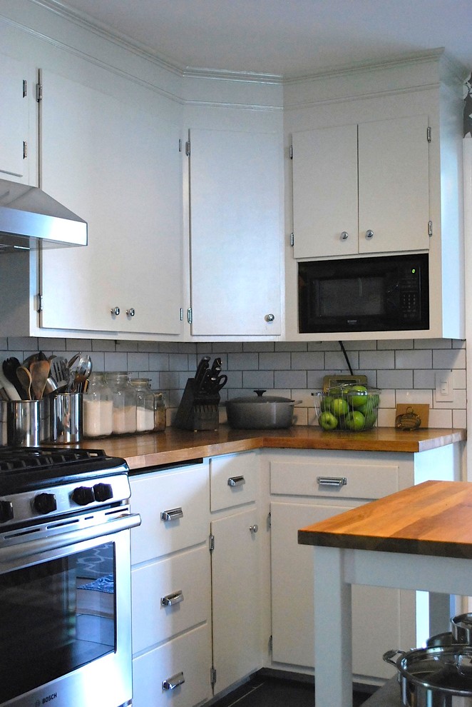 Elegant kitchen photo in Boston with flat-panel cabinets, white cabinets, wood countertops, white backsplash, subway tile backsplash and stainless steel appliances
