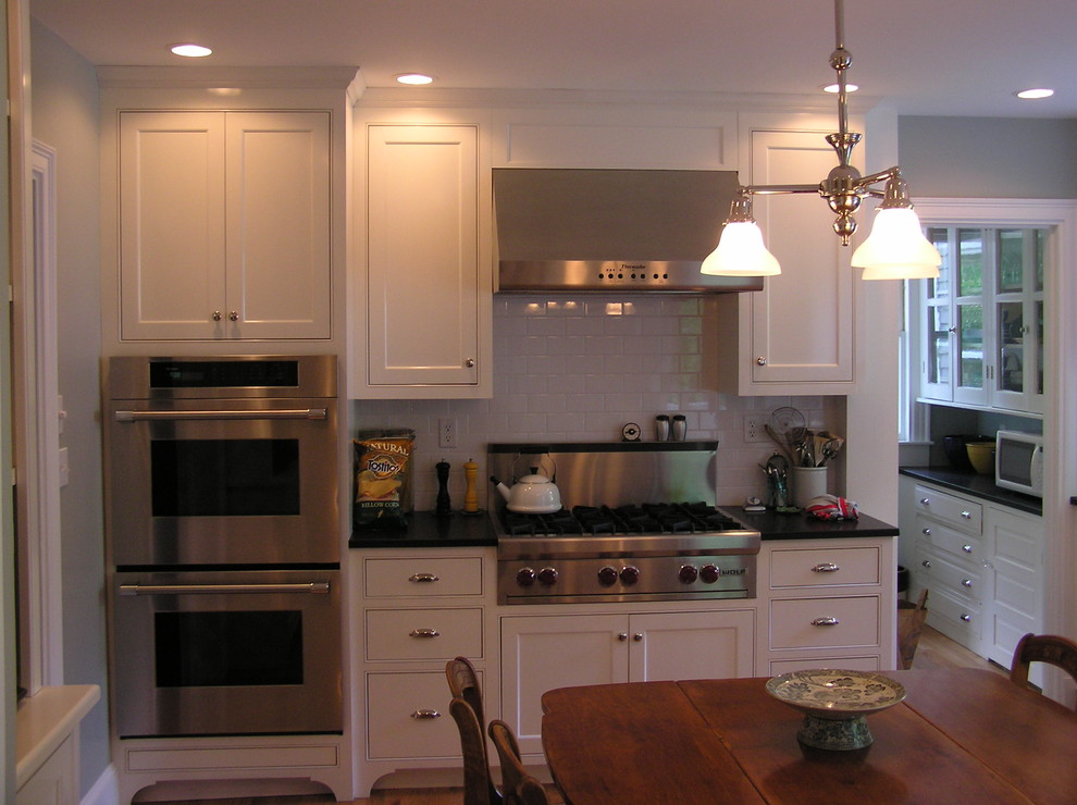 Example of a classic kitchen design in Boston with stainless steel appliances, subway tile backsplash, white backsplash and beaded inset cabinets