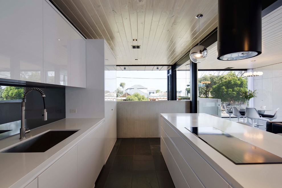 Foto de cocina actual con fregadero integrado, puertas de armario blancas, salpicadero negro y una isla