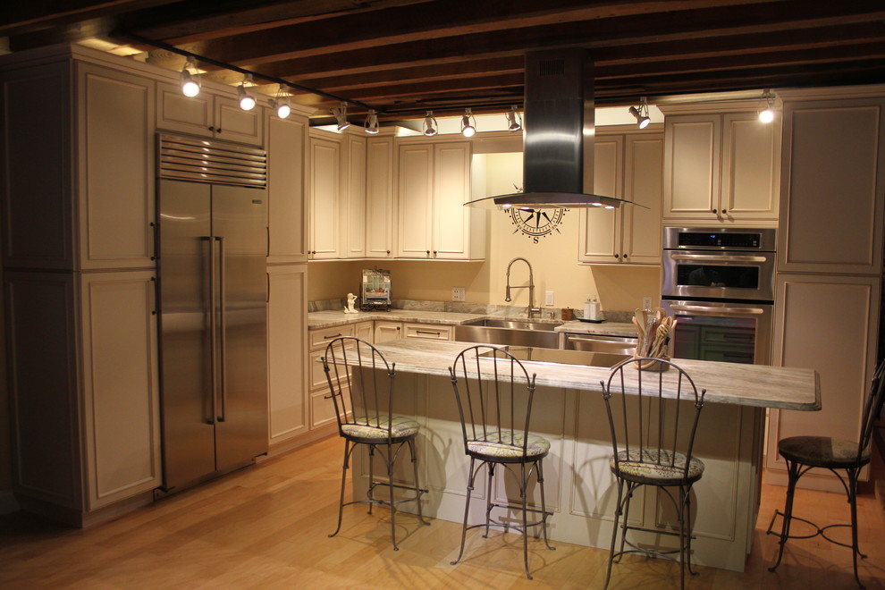 Bild på ett mellanstort rustikt kök, med en rustik diskho, släta luckor, vita skåp, granitbänkskiva, beige stänkskydd, rostfria vitvaror, ljust trägolv och en köksö