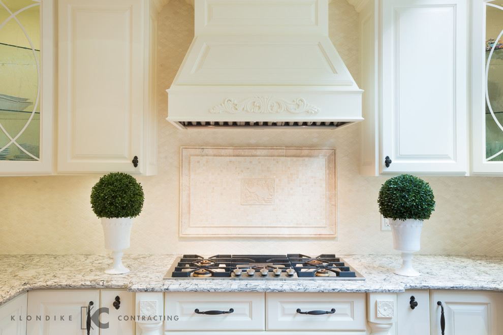 Inredning av ett klassiskt mellanstort kök, med en undermonterad diskho, luckor med upphöjd panel, gula skåp, bänkskiva i kvarts, beige stänkskydd, stänkskydd i stenkakel, rostfria vitvaror, mellanmörkt trägolv och en halv köksö