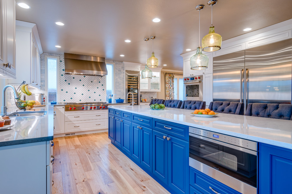 Bild på ett stort vintage vit vitt kök, med en undermonterad diskho, luckor med profilerade fronter, blå skåp, bänkskiva i kvarts, flerfärgad stänkskydd, stänkskydd i porslinskakel, rostfria vitvaror, ljust trägolv, en köksö och beiget golv