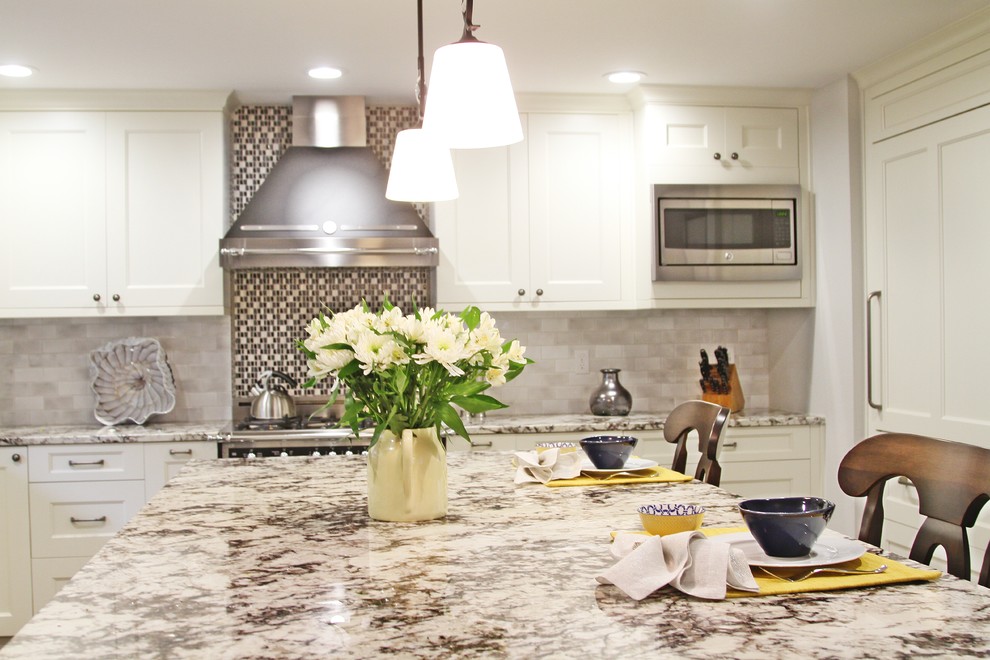 Example of a transitional eat-in kitchen design in Seattle with recessed-panel cabinets, white cabinets, granite countertops, beige backsplash, stone tile backsplash, stainless steel appliances and an island