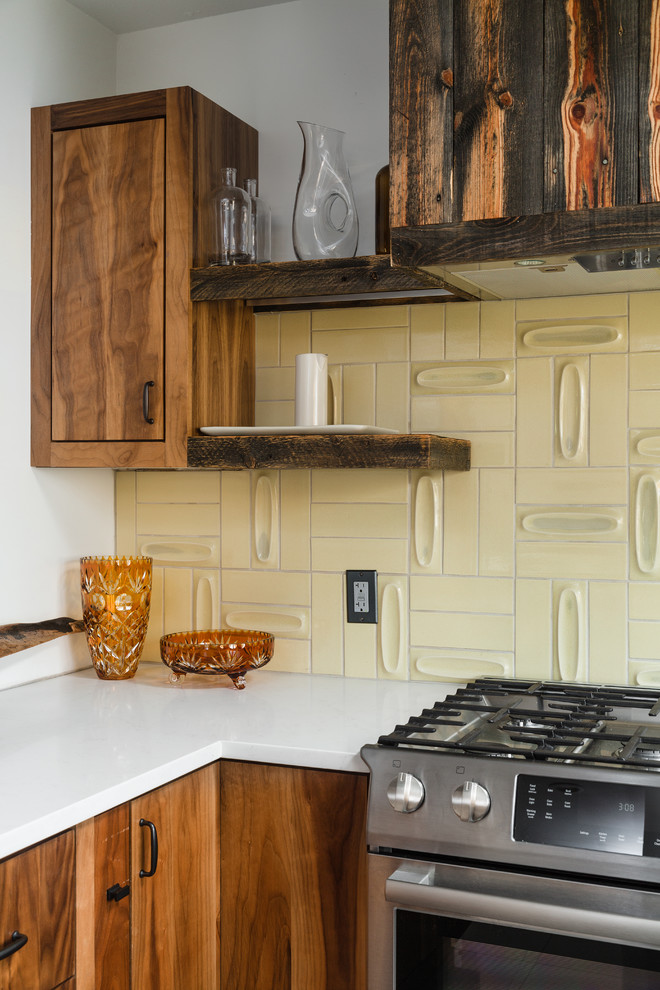 Kleine Stilmix Küche in L-Form mit flächenbündigen Schrankfronten, hellbraunen Holzschränken, Küchenrückwand in Gelb, Küchengeräten aus Edelstahl und Kücheninsel in Denver