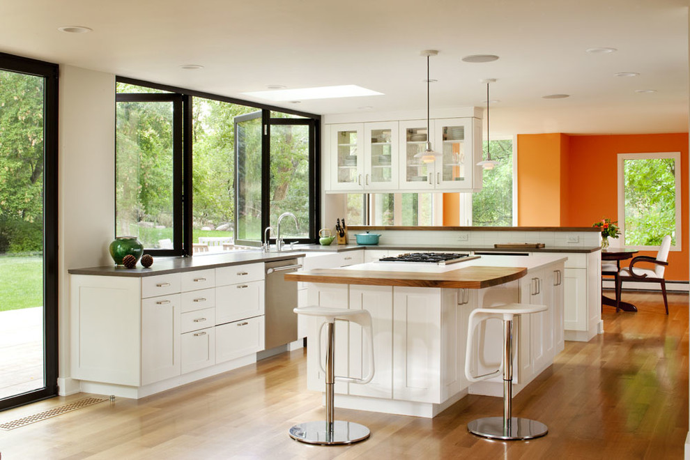 Klassische Küche mit Arbeitsplatte aus Holz, Schrankfronten im Shaker-Stil, weißen Schränken, Küchenrückwand in Weiß und Küchengeräten aus Edelstahl in Denver