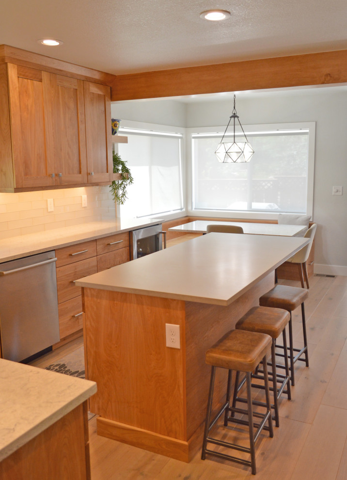 Mid-sized transitional u-shaped light wood floor, gray floor and exposed beam eat-in kitchen photo in Denver with an undermount sink, shaker cabinets, medium tone wood cabinets, quartz countertops, white backsplash, glass tile backsplash, stainless steel appliances, an island and multicolored countertops