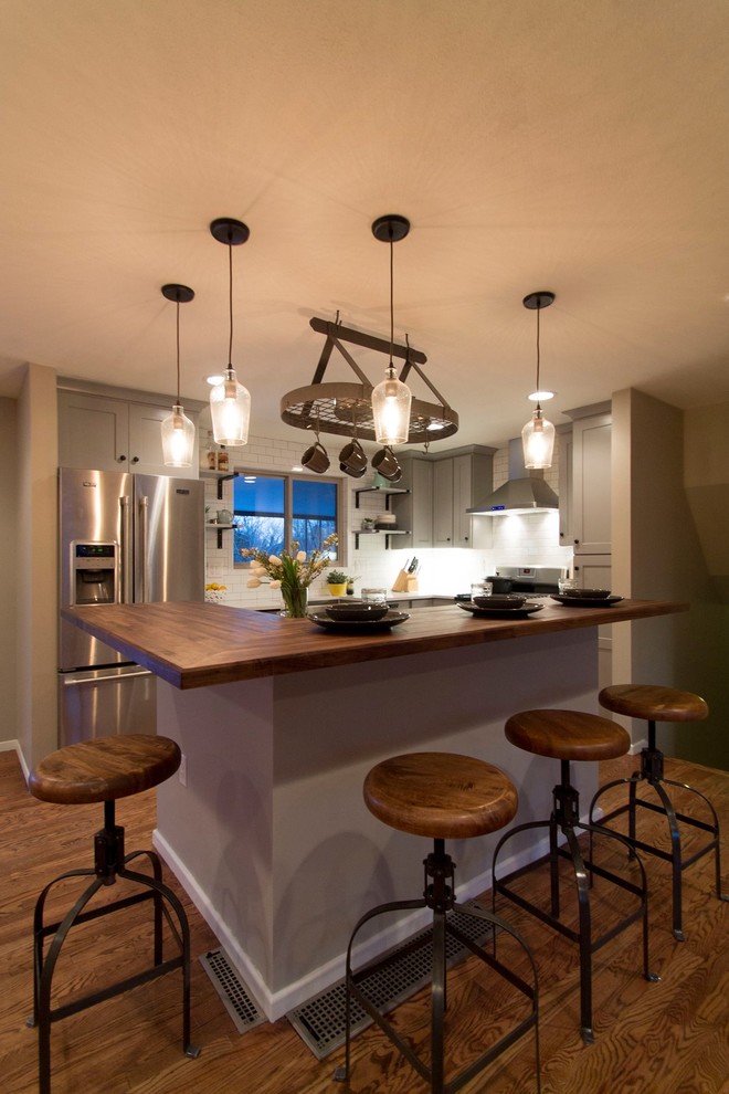 Klassisk inredning av ett mellanstort kök, med en rustik diskho, skåp i shakerstil, grå skåp, bänkskiva i kvarts, vitt stänkskydd, stänkskydd i keramik, rostfria vitvaror, mellanmörkt trägolv och en köksö