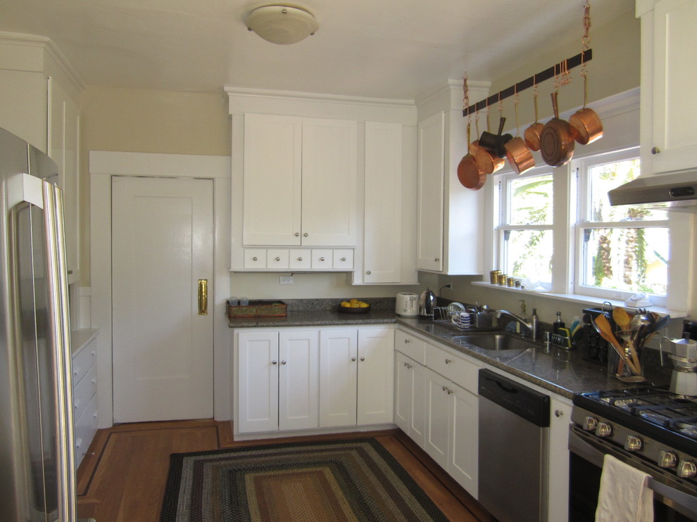This is an example of a small classic galley enclosed kitchen in San Francisco with a submerged sink, shaker cabinets, white cabinets, granite worktops, grey splashback, stone slab splashback, stainless steel appliances, light hardwood flooring and no island.