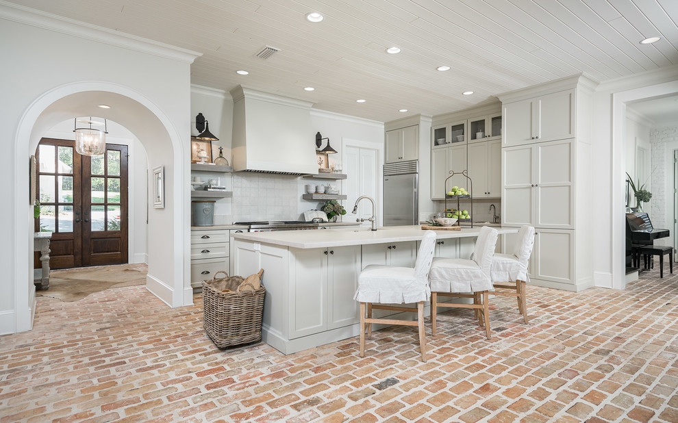 Küche in L-Form mit Betonarbeitsplatte, Rückwand aus Mosaikfliesen, Küchengeräten aus Edelstahl, Backsteinboden und Kücheninsel in Sonstige