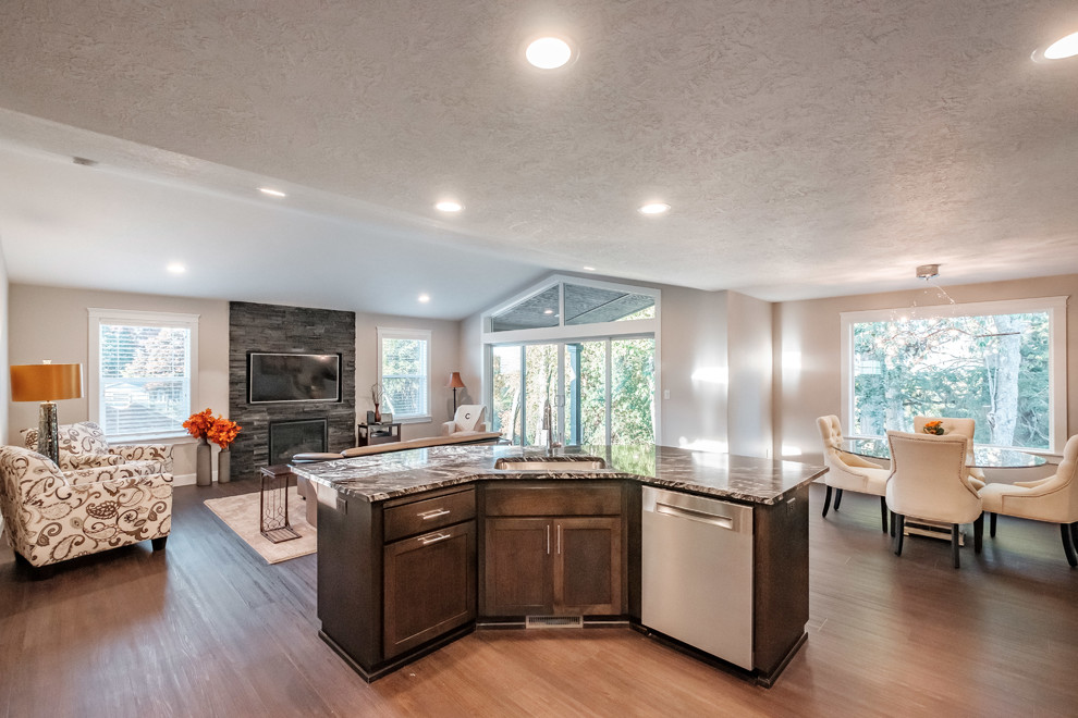 Modern inredning av ett flerfärgad flerfärgat kök med öppen planlösning, med en undermonterad diskho, skåp i mörkt trä, granitbänkskiva, rostfria vitvaror, en köksö, brunt golv och skåp i shakerstil