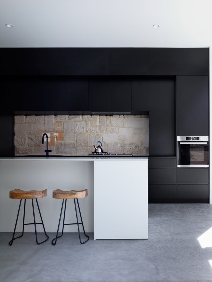 シドニーにあるコンテンポラリースタイルのおしゃれなアイランドキッチン (フラットパネル扉のキャビネット、黒いキャビネット、ベージュキッチンパネル、シルバーの調理設備、コンクリートの床、グレーの床、白いキッチンカウンター) の写真