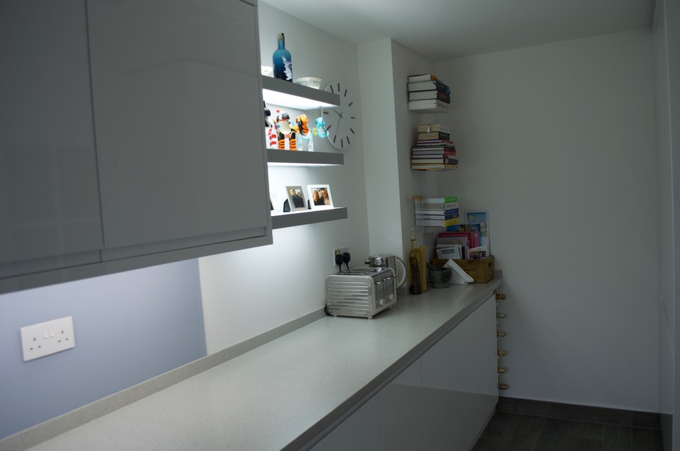 Ejemplo de cocina contemporánea pequeña cerrada con fregadero integrado, armarios con paneles lisos, puertas de armario blancas, encimera de acrílico, salpicadero azul, salpicadero de vidrio templado y electrodomésticos blancos