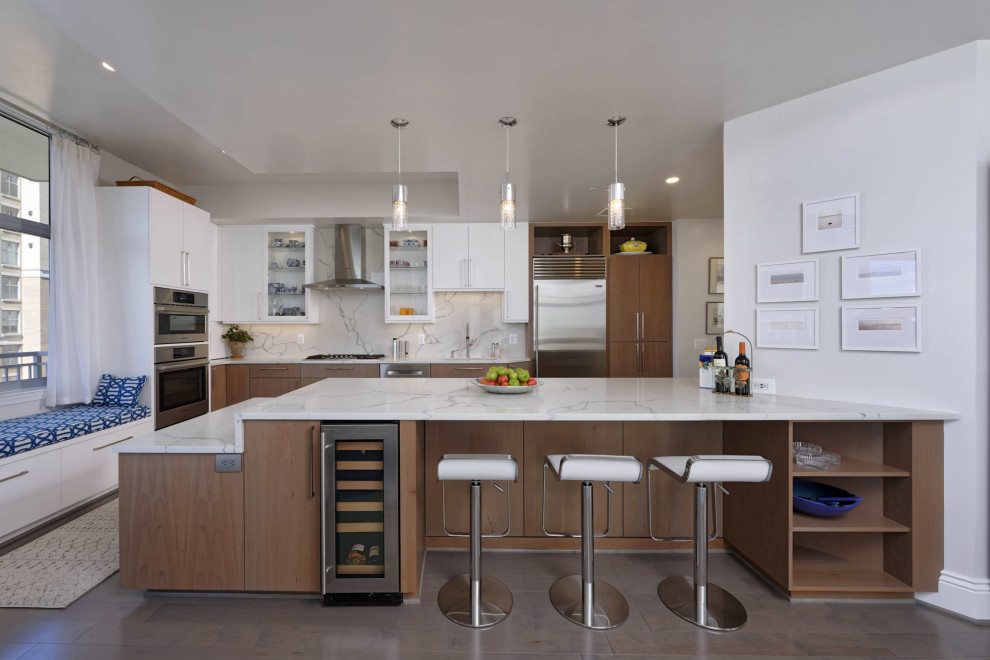 Kitchen - contemporary l-shaped gray floor kitchen idea in DC Metro with an undermount sink, flat-panel cabinets, medium tone wood cabinets, white backsplash, stainless steel appliances, a peninsula and white countertops
