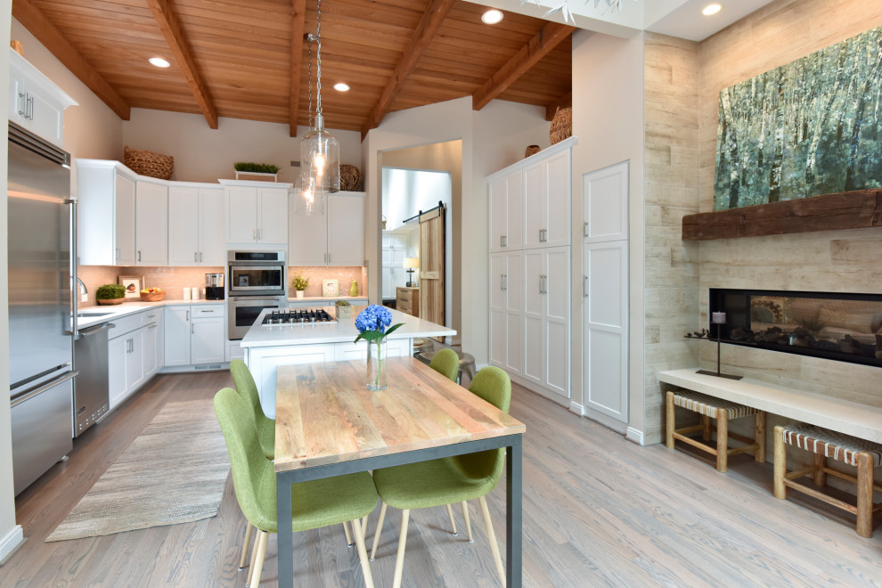 Example of a country u-shaped light wood floor, beige floor and wood ceiling kitchen design in DC Metro with an undermount sink, shaker cabinets, white cabinets, gray backsplash, stainless steel appliances, an island and white countertops
