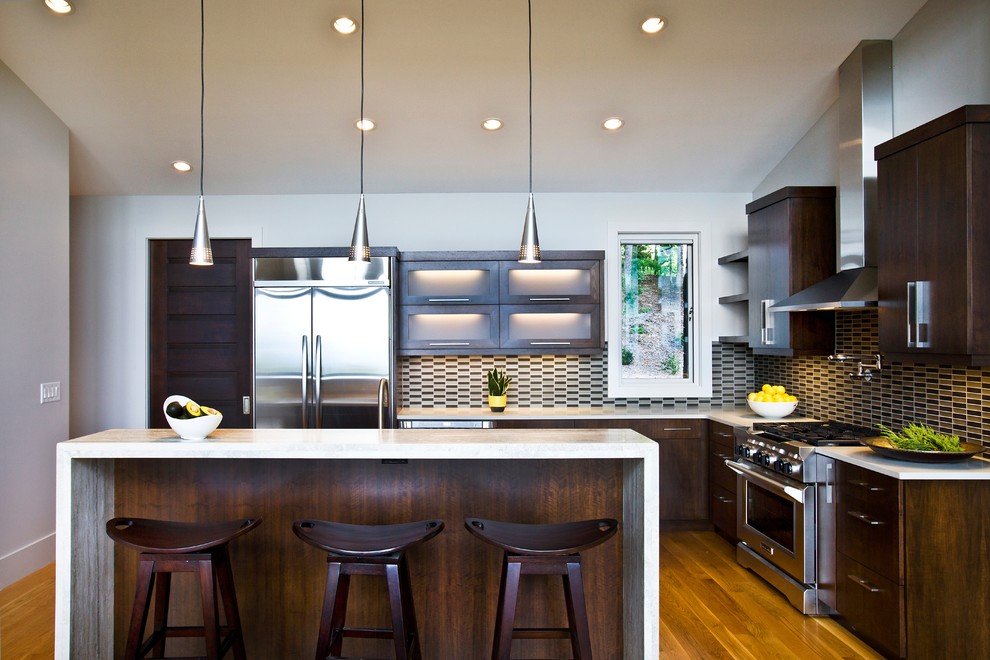 Foto de cocinas en L contemporánea con electrodomésticos de acero inoxidable, armarios con paneles lisos, puertas de armario de madera en tonos medios y salpicadero multicolor
