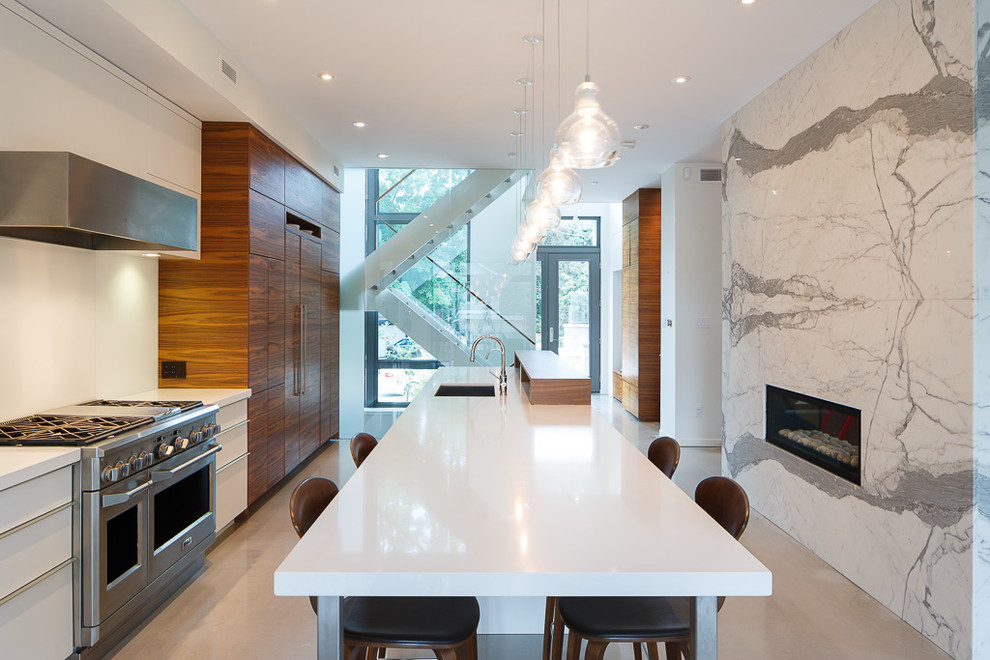 This is an example of a contemporary galley kitchen in Ottawa with a submerged sink, flat-panel cabinets, medium wood cabinets, white splashback, stainless steel appliances and an island.