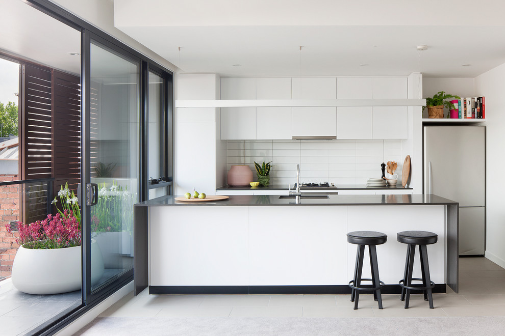 Inspiration for a contemporary kitchen remodel in Melbourne with a drop-in sink, white cabinets, white backsplash, ceramic backsplash, stainless steel appliances and an island