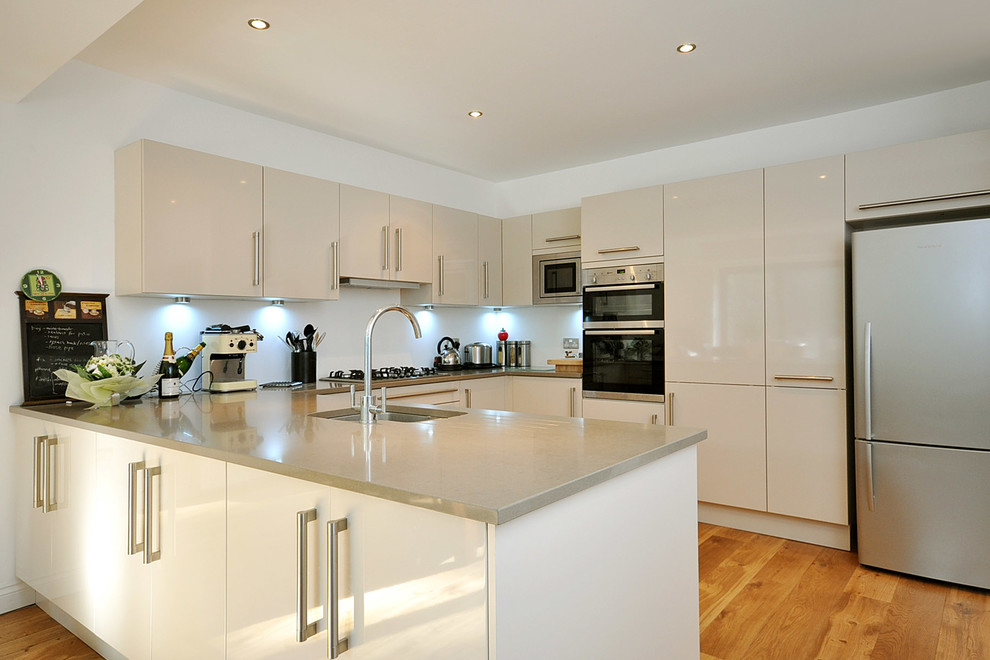 Moderne Wohnküche mit Waschbecken, offenen Schränken, weißen Schränken, Granit-Arbeitsplatte, Küchenrückwand in Grau, Rückwand aus Metallfliesen, Küchengeräten aus Edelstahl, gebeiztem Holzboden und Kücheninsel in London