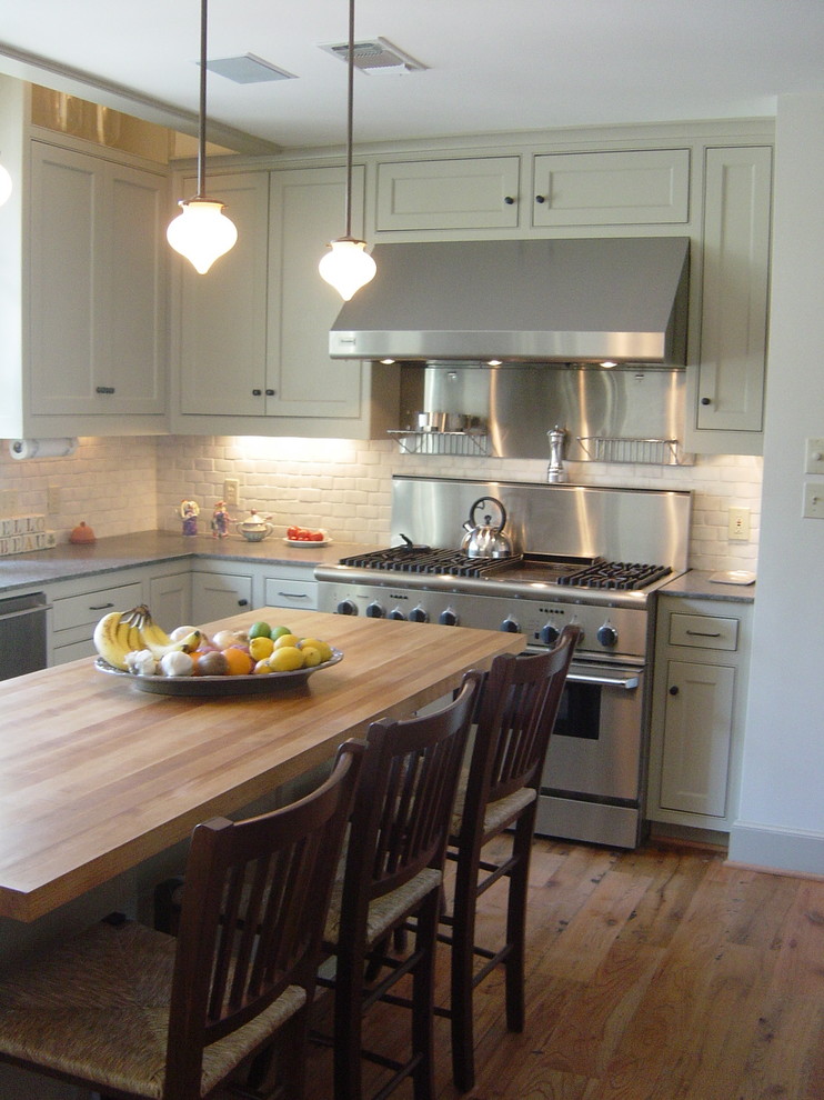 オースティンにあるトラディショナルスタイルのおしゃれなキッチン (シルバーの調理設備、木材カウンター、青いキャビネット、白いキッチンパネル) の写真