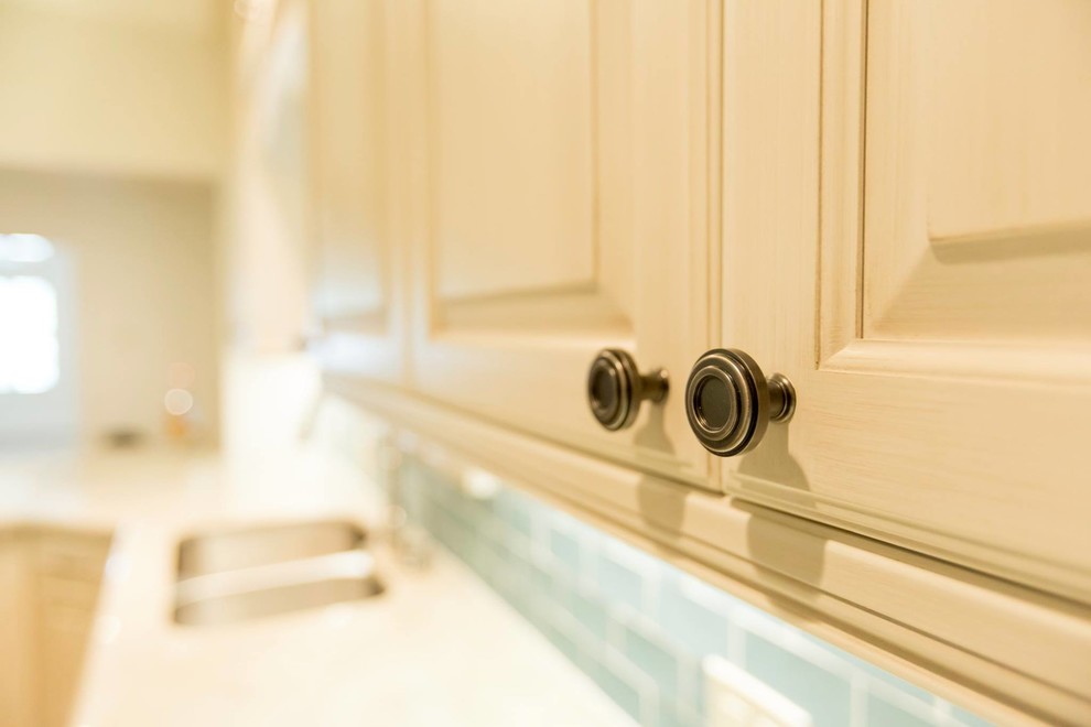 Exempel på ett mellanstort klassiskt vit vitt kök, med en undermonterad diskho, luckor med upphöjd panel, vita skåp, bänkskiva i kalksten, blått stänkskydd, stänkskydd i tunnelbanekakel, rostfria vitvaror, klinkergolv i porslin, en köksö och brunt golv