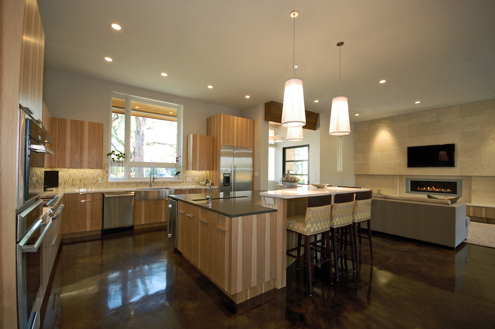 На фото: угловая кухня-гостиная в современном стиле с техникой из нержавеющей стали, с полувстраиваемой мойкой (с передним бортиком), плоскими фасадами и фасадами цвета дерева среднего тона