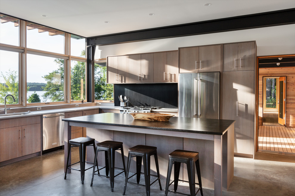 Inspiration for a contemporary l-shaped kitchen/diner in Minneapolis with a submerged sink, flat-panel cabinets, light wood cabinets, window splashback, stainless steel appliances, concrete flooring, an island, grey floors and black worktops.