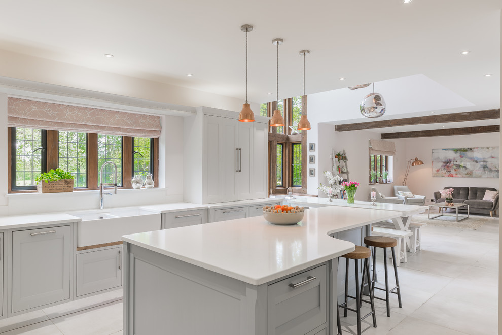Offene Klassische Küche in grau-weiß mit Landhausspüle, Schrankfronten mit vertiefter Füllung, grauen Schränken, Kücheninsel und weißem Boden in Hertfordshire