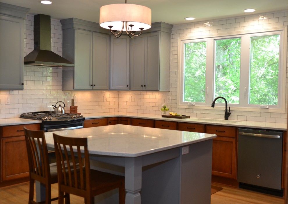 Bild på ett mellanstort eklektiskt kök, med en undermonterad diskho, skåp i shakerstil, grå skåp, bänkskiva i kvarts, vitt stänkskydd, stänkskydd i tunnelbanekakel, rostfria vitvaror, mellanmörkt trägolv, en köksö och brunt golv