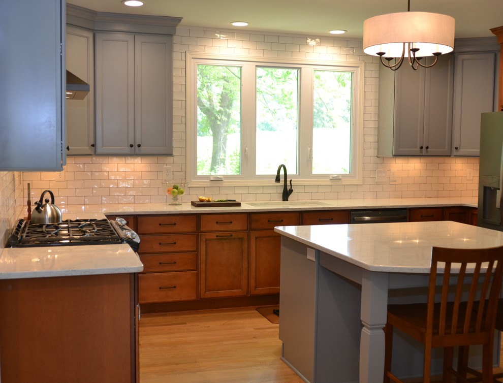 Exempel på ett mellanstort eklektiskt kök, med en undermonterad diskho, skåp i shakerstil, grå skåp, bänkskiva i kvarts, vitt stänkskydd, stänkskydd i tunnelbanekakel, rostfria vitvaror, mellanmörkt trägolv, en köksö och brunt golv