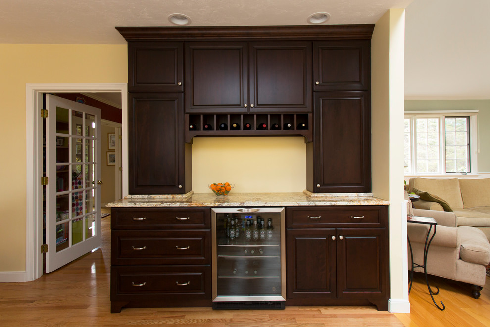 Modelo de cocina tradicional abierta con armarios con paneles con relieve, puertas de armario de madera en tonos medios, encimera de granito y electrodomésticos de acero inoxidable