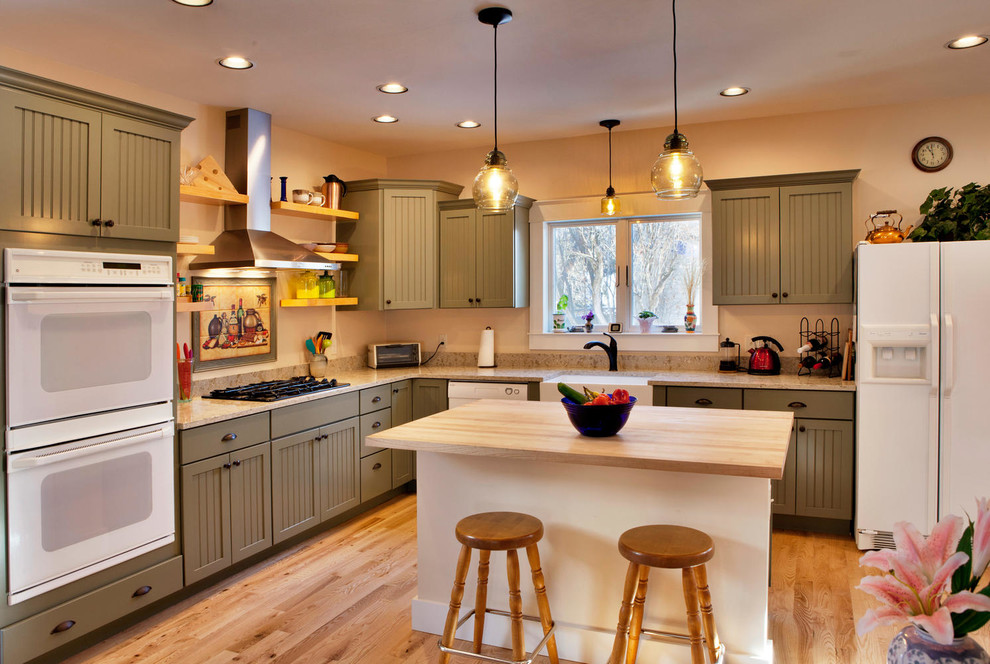 Mittelgroße Urige Küche in L-Form mit Landhausspüle, Schrankfronten im Shaker-Stil, grünen Schränken, weißen Elektrogeräten, braunem Holzboden, Kücheninsel, braunem Boden und beiger Arbeitsplatte in Sonstige