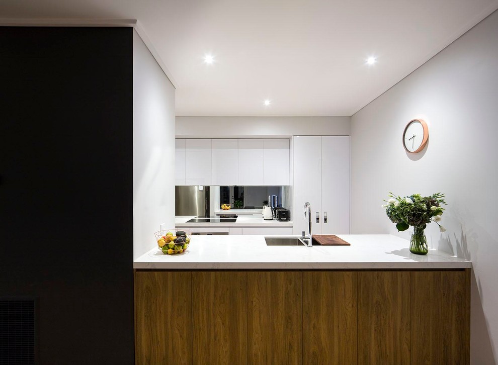 Moderne Küche mit Doppelwaschbecken, weißen Schränken, Granit-Arbeitsplatte, bunter Rückwand, Rückwand aus Spiegelfliesen, Küchengeräten aus Edelstahl und hellem Holzboden in Melbourne