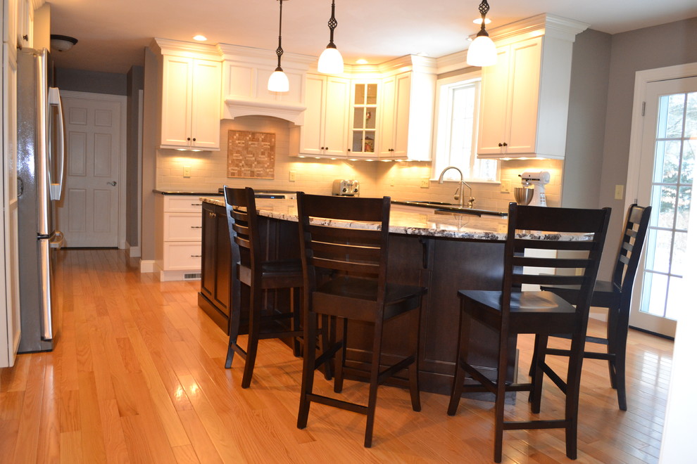 Eat-in kitchen - large traditional u-shaped light wood floor eat-in kitchen idea in Boston with a single-bowl sink, recessed-panel cabinets, white cabinets, granite countertops, white backsplash, subway tile backsplash, stainless steel appliances and an island