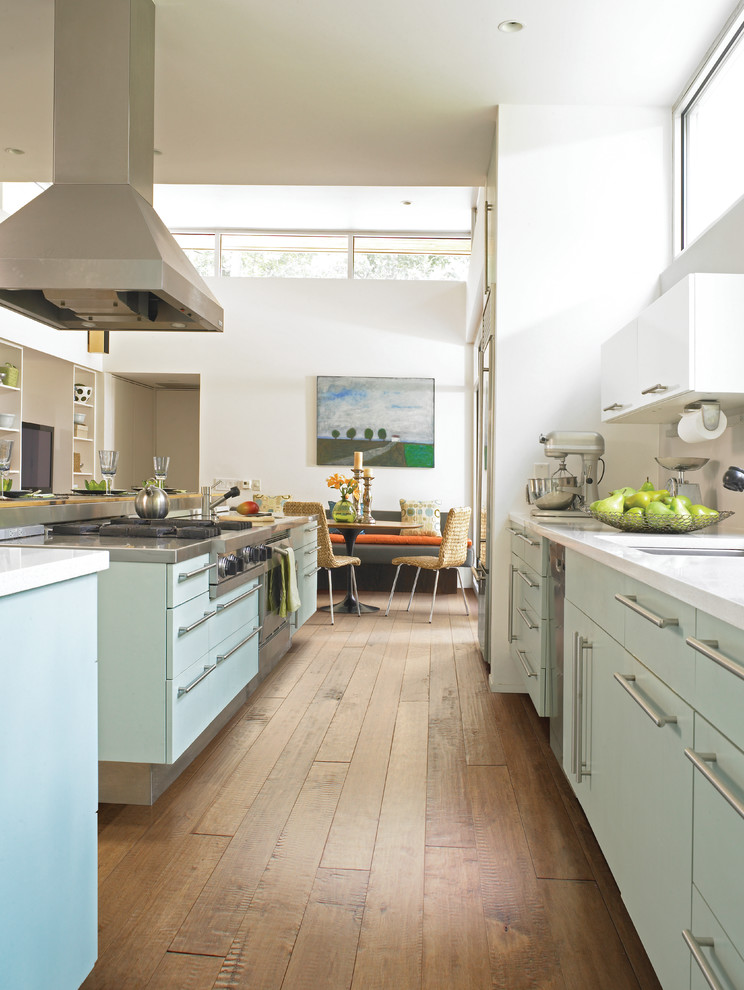 Inspiration för stora moderna kök, med släta luckor, blå skåp, mellanmörkt trägolv, en köksö, en undermonterad diskho, rostfria vitvaror, brunt golv och bänkskiva i koppar