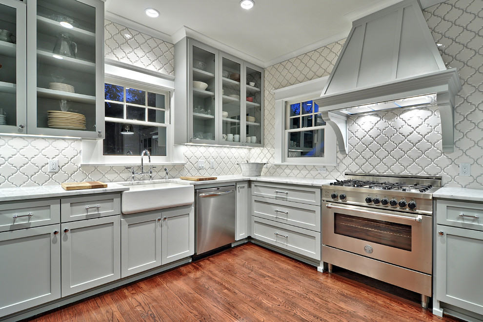 Klassische Küche mit Landhausspüle, grauen Schränken, Küchenrückwand in Weiß, Küchengeräten aus Edelstahl und dunklem Holzboden in Austin