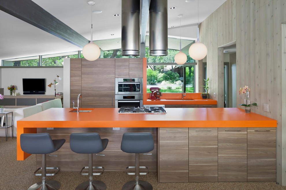 Mid-sized 1960s galley brown floor open concept kitchen photo in Austin with an undermount sink, flat-panel cabinets, medium tone wood cabinets, stainless steel appliances, an island, quartz countertops and orange countertops