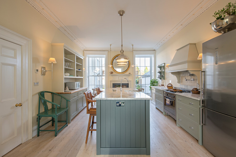Large traditional kitchen/diner in Dublin with a submerged sink, shaker cabinets, green cabinets, granite worktops, white splashback, ceramic splashback, stainless steel appliances, light hardwood flooring and an island.