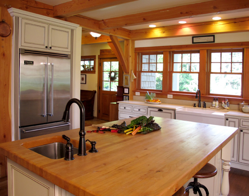 Geschlossene Rustikale Küche in L-Form mit Landhausspüle, Kassettenfronten, weißen Schränken, Arbeitsplatte aus Holz, Küchengeräten aus Edelstahl, braunem Holzboden, Kücheninsel und braunem Boden in Seattle